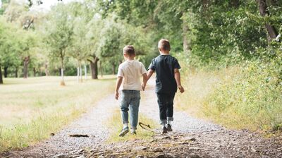 Two boys wearing barefoot socks on a forest path