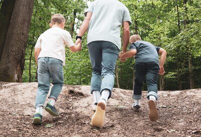 Father with his two sons on a forest path, wearing barefoot socks and barefoot shoes
