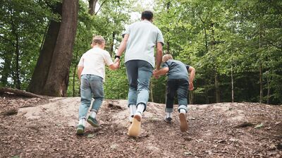 Father with his two sons on a forest path, wearing barefoot socks and barefoot shoes